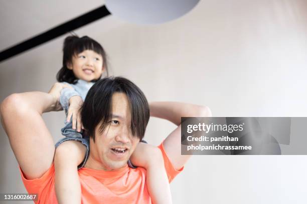 asian kid riding on the nect her dad in home. - nect stock pictures, royalty-free photos & images