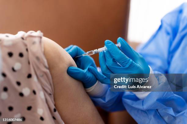 close-up of nurse vaccinating woman during home visit - ordre de rester à la maison photos et images de collection