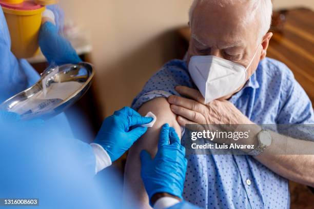 covid-19 vaccination of a senior man at home - flu vaccine foto e immagini stock