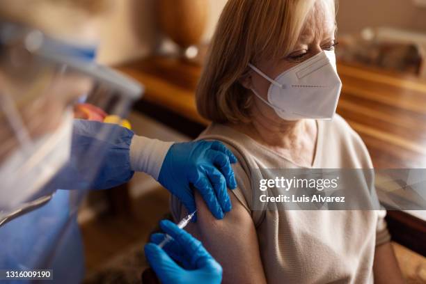 senior woman receiving vaccination at home - illness prevention stock pictures, royalty-free photos & images