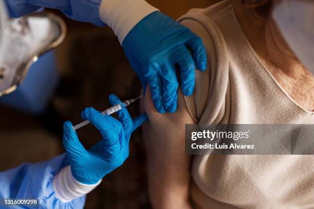 senior female getting vaccinated at home - injecting foto e immagini stock