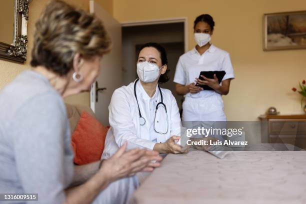 health caregiver explaining medication to elderly patient - tablettenbox deutsch stock-fotos und bilder