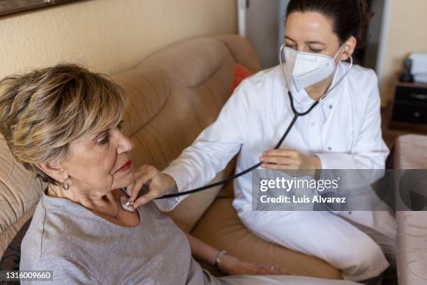 medical worker examining senior patient on house call - patientin stock-fotos und bilder