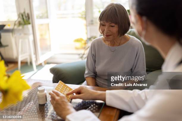 healthcare worker giving medicine to elderly woman at home - dosing stock-fotos und bilder