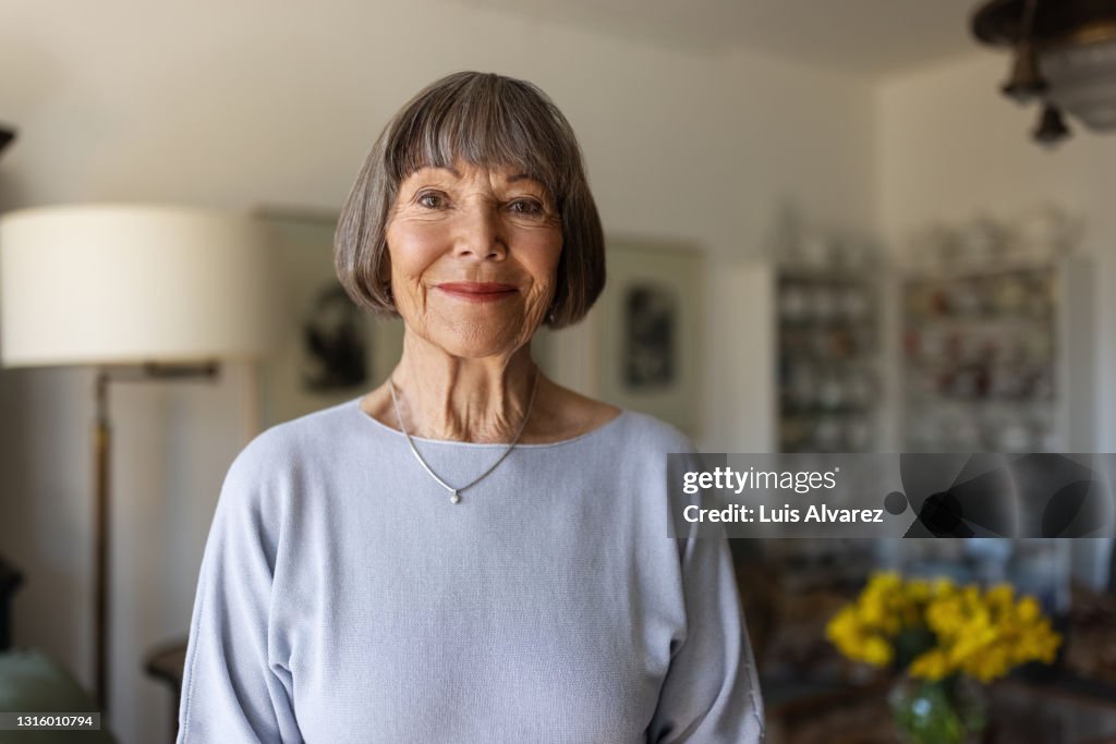 Portrait of a happy senior woman standing in her home