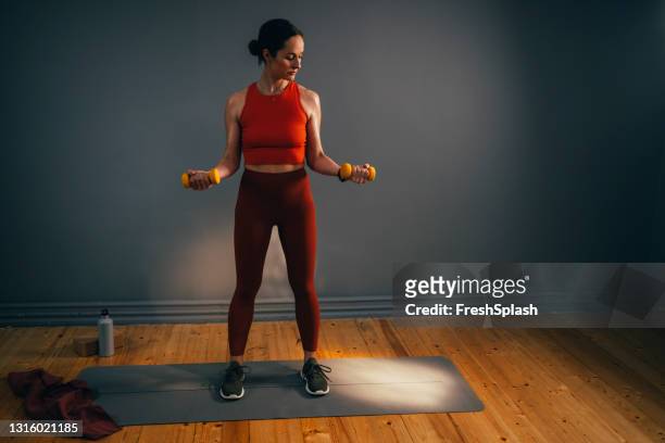 fit junge kaukasische frau training in einem indoor-fitnessstudio - woman standing exercise stock-fotos und bilder