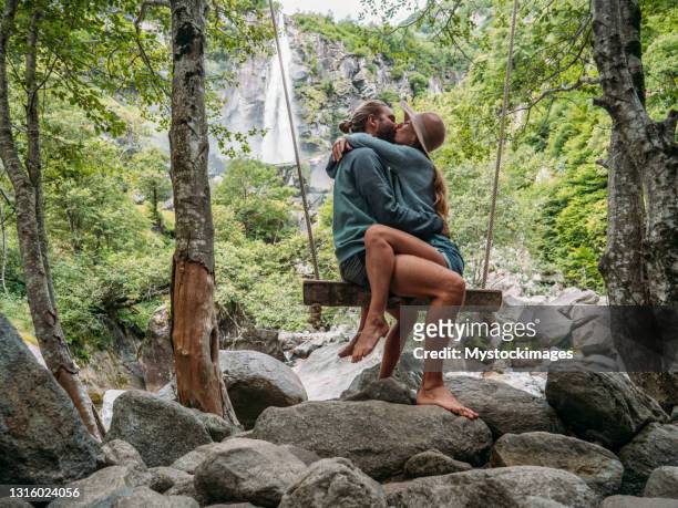 paar umarmt auf holzschaukel in der nähe von wasserfall - couple forest stock-fotos und bilder