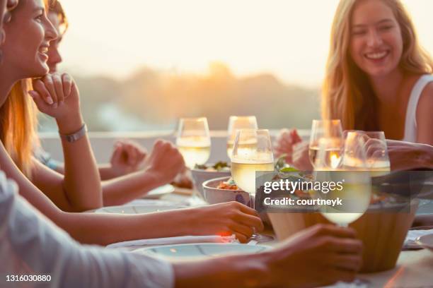 en grupp vänner dricker vitt vin vid bordet på en middagsbjudning. - patio party bildbanksfoton och bilder