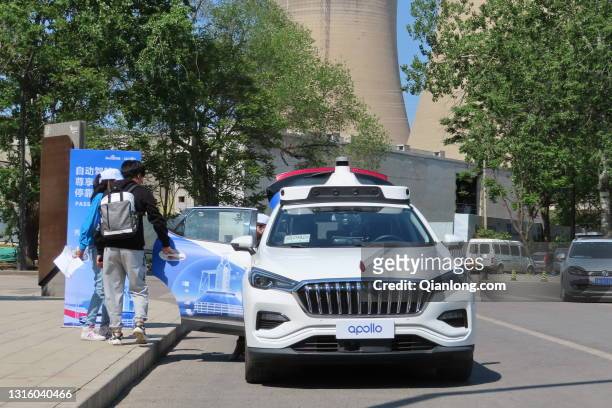 Customers get in an Apollo Robotaxi at Shougang Park as Baidu launches China's first driverless taxi service in the city on May 2, 2021 in Beijing,...
