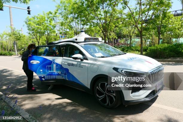 Customers get in an Apollo Robotaxi at Shougang Park as Baidu launches China's first driverless taxi service in the city on May 2, 2021 in Beijing,...