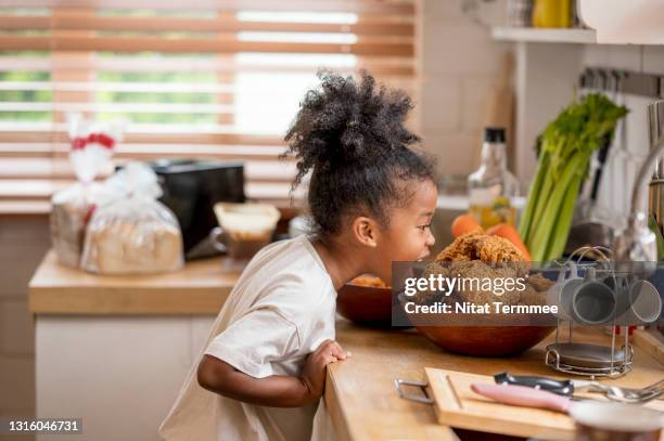 little african cute girl smelling fried chicken served in tray. enjoy eating every day. - day in the life series fotografías e imágenes de stock