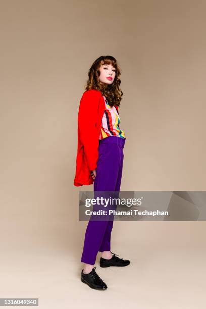 fashionable woman standing in front of plain background - purple coat fotografías e imágenes de stock