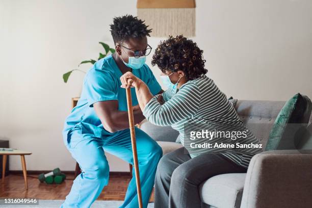ontsproten van een jonge mannelijke verpleegster die een bejaarde geduldige tribune helpt - caregiver and senior stockfoto's en -beelden