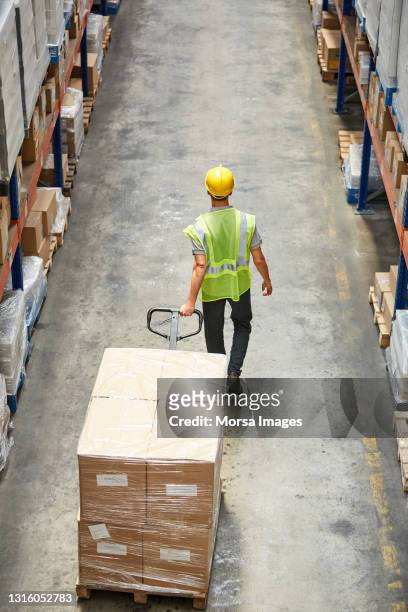 worker pulling merchandise at warehouse aisle - ameisenstraße stock-fotos und bilder