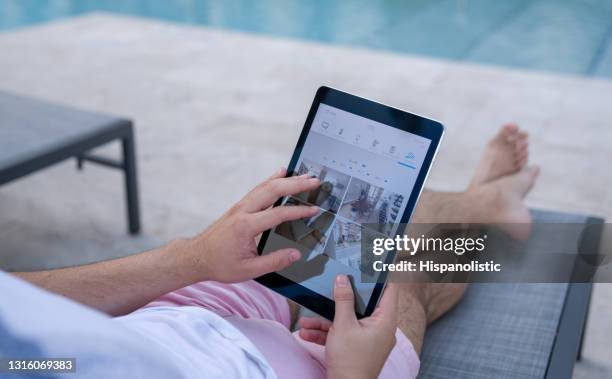 plan rapproché sur un homme près de la piscine surveillant sa maison avec des caméras de surveillance - camera de surveillance photos et images de collection