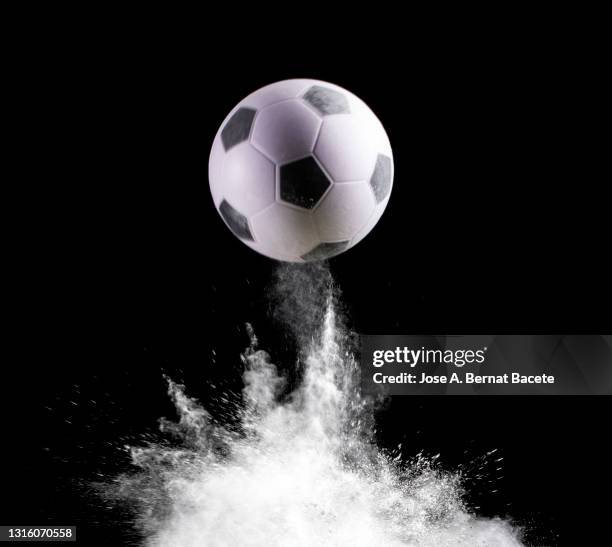 impact and rebound of a ball of soccer on a surface of land and powder on a black background - hallenfußball wettbewerb stock-fotos und bilder