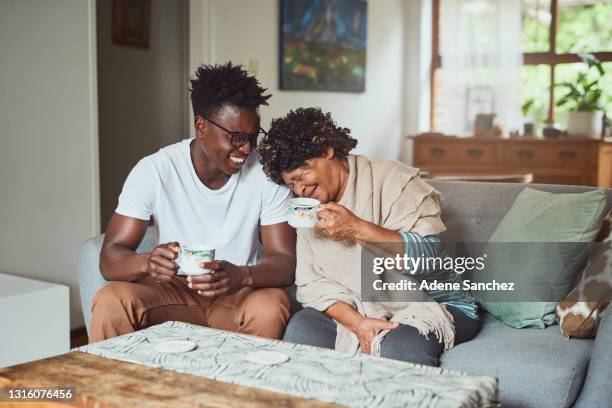 eine großmutter und ihr enkel genießen eine tasse kaffee zusammen zu hause - mom sits on sons lap stock-fotos und bilder