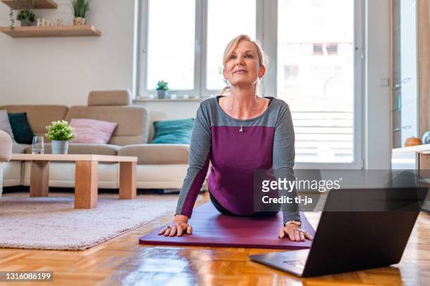 donna adulta matura che esercita in un soggiorno - 55 59 anni foto e immagini stock