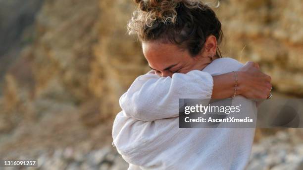 young woman practices yoga on sandy beach - hugging self stock pictures, royalty-free photos & images