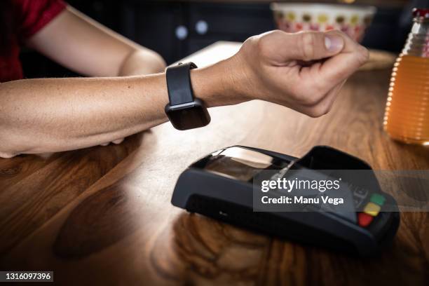 woman paying contactless with smartwatch in restaurant - smartwatch pay stock-fotos und bilder