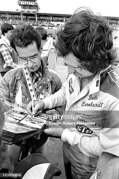 Driver Dale Earnhardt Sr. Signs an autograph for a fan prior to the start of the 1981 Daytona 500 stock car race at Daytona International Speedway in...