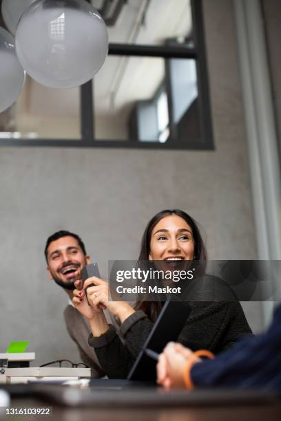 smiling businesswoman talking with colleagues during meeting at office - arab people laugh stock-fotos und bilder