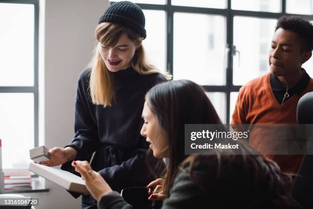 female and male coworkers discussing over product in office - プロトタイプ ストックフォトと画像