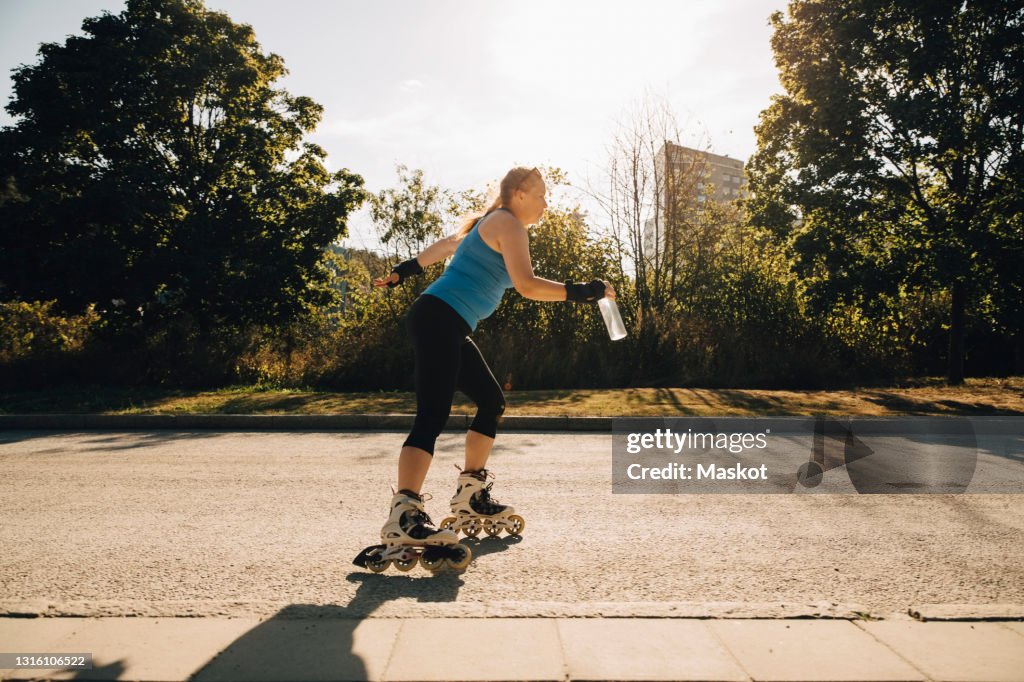 Female athlete roller skating on street during sunny day