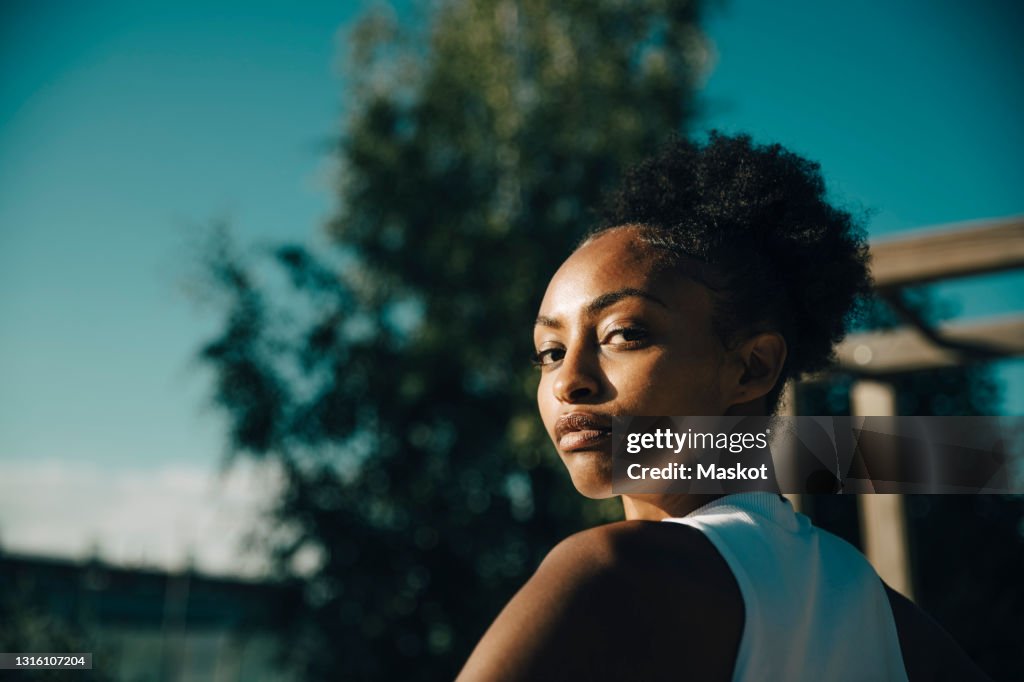 Portrait of female athlete looking over shoulder on sunny day