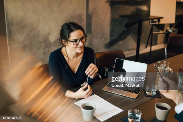 smiling businesswoman in discussion with colleague during meeting at office - business meeting coffee stock pictures, royalty-free photos & images