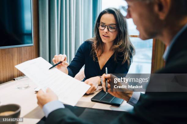 male and female entrepreneur brainstorming over document during meeting in office - juristische funktion stock-fotos und bilder