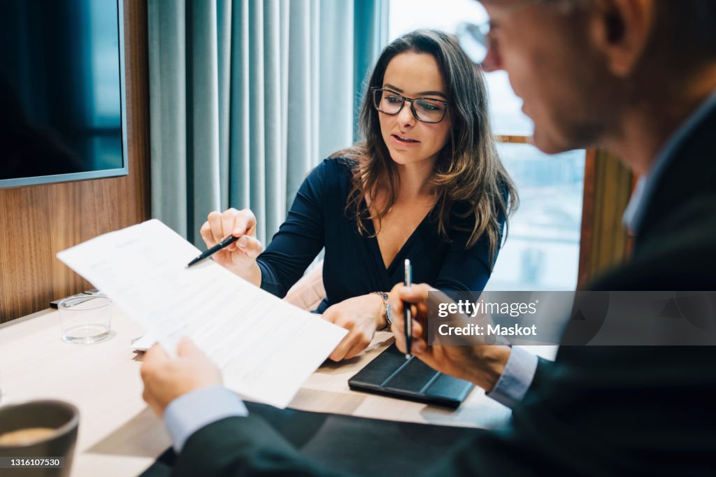 Male and female entrepreneur brainstorming over document during meeting in office