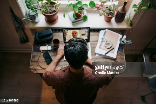 directly above shot of businessman on video call through laptop with male colleague at home office - telecommuting stock pictures, royalty-free photos & images