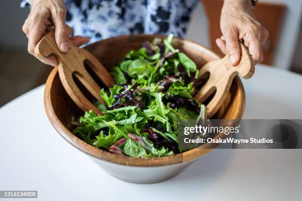 female hands mixing various vegetable in wooden salad bowl. - grönsallad bildbanksfoton och bilder