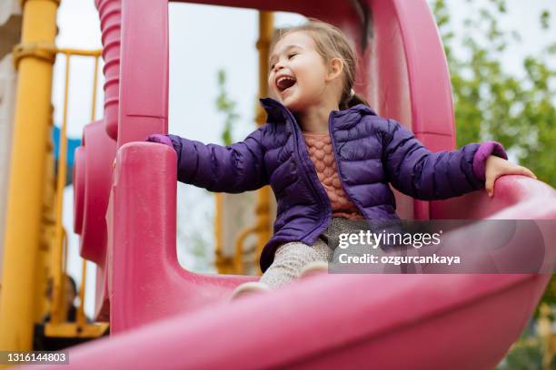 a 2-3 year old girl who slides off the slide is very happy, positive emotion - 5 year stock pictures, royalty-free photos & images
