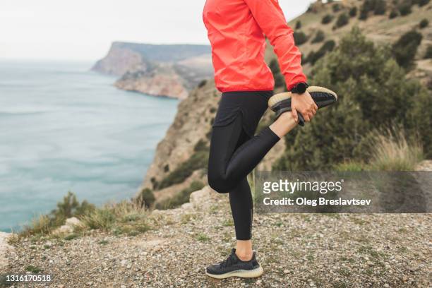female athlete stretching and warming up before running outdoors. legs and hand with smartwatch close-up. unrecognizable person. - warm up exercise stockfoto's en -beelden