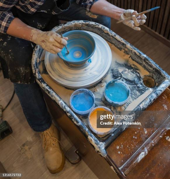 mãos de uma jovem fazendo cerâmica usando uma roda de cerâmica, colorindo a tigela - cobrindo-a com um esmalte. - glazed food - fotografias e filmes do acervo