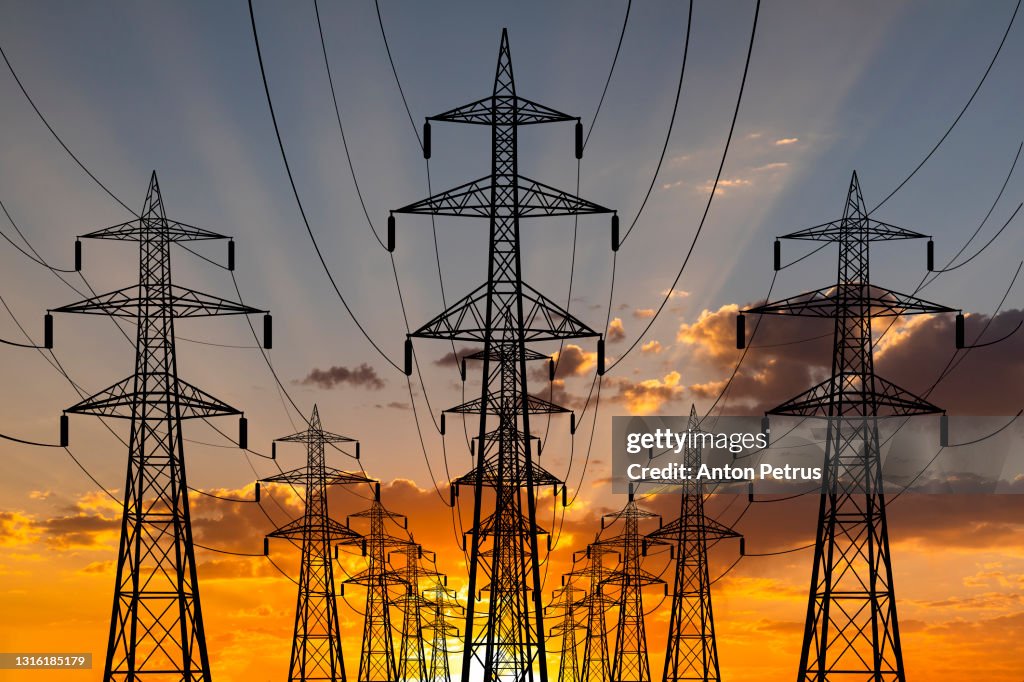 High voltage towers at sunset background. Power lines against the sky