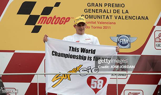 Viessmann Kiefer Racing's German Stefan Bradl holds a banner in tribute of San Carlo Honda Gresini's Italian Marco Simoncelli on the posdium of the...