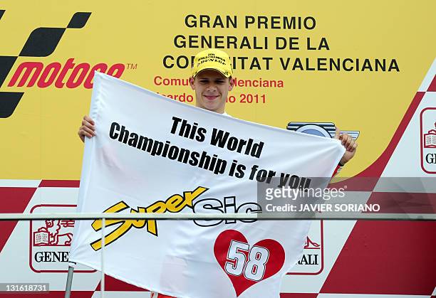 Viessmann Kiefer Racing's German Stefan Bradl holds a banner in memory of San Carlo Honda Gresini's Italian Marco Simoncelli on the posdium of the...