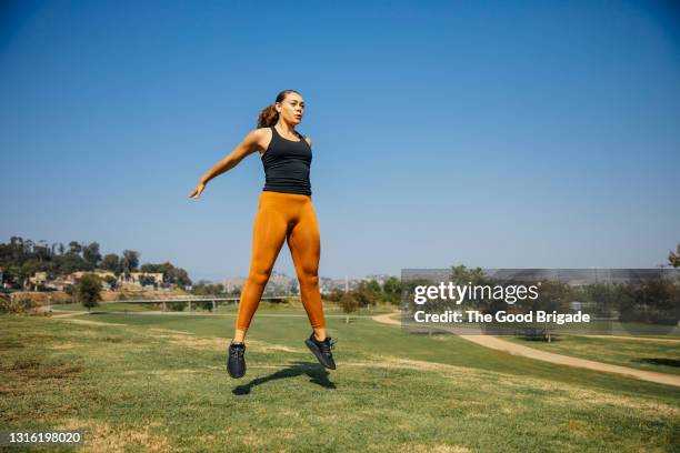 determined young women jumping while exercising at park against sky - bodyweight training stock pictures, royalty-free photos & images