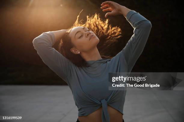 female dancer with eyes closed dancing during sunset - goldene stunde stock-fotos und bilder