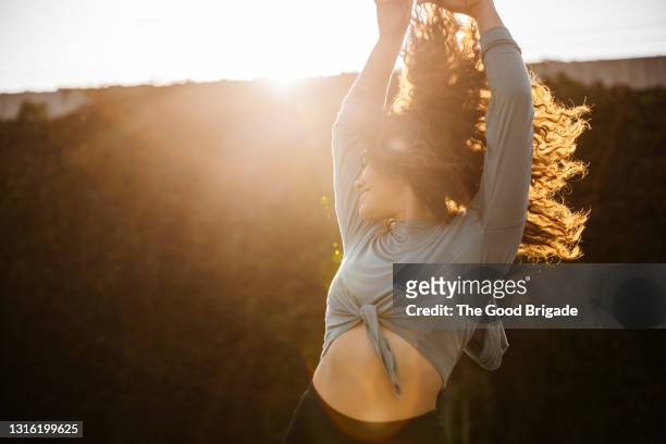 female dancer enjoying while dancing during sunset - arme hoch stock-fotos und bilder