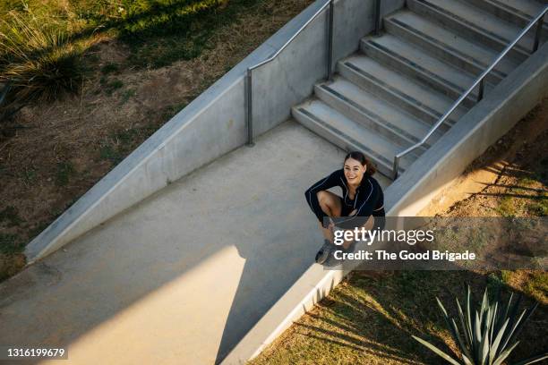 cheerful young woman sitting on wall at park - person look up from above stock pictures, royalty-free photos & images