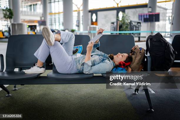 junge frau wartet auf verspäteten flug und lesen digitales buch auf stühlen - flying reading stock-fotos und bilder