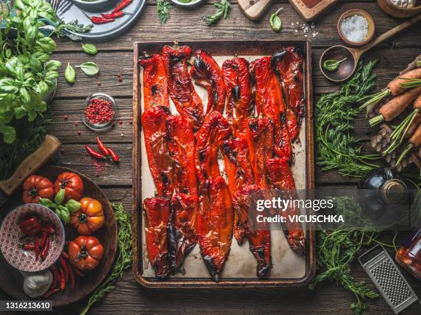 roasted red pepper on baking tray framed by various ingredients and kitchen utensils - pimentão vermelho assado - fotografias e filmes do acervo