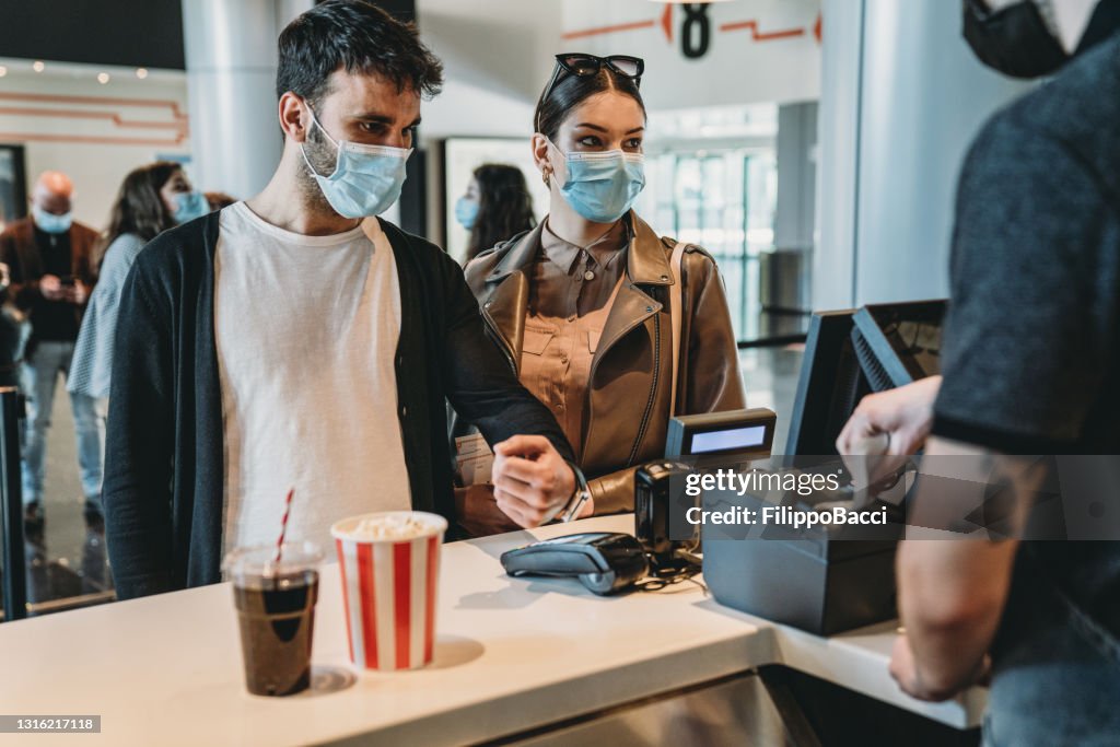 Millennial man is paying with a contactless smart watch at the movie theater's bar counter