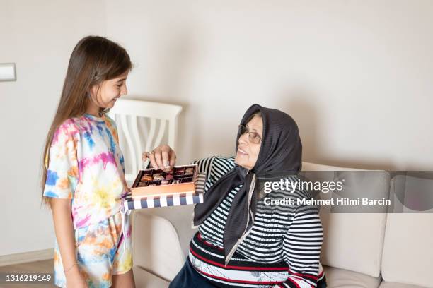 enkelin bietet pralinen an großmutter - child loves chocolates stock-fotos und bilder