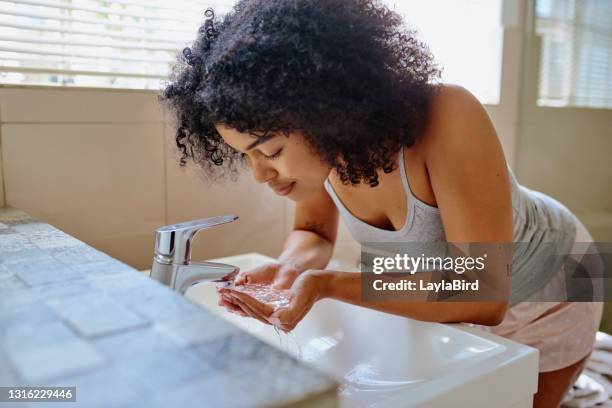 schuss einer schönen jungen frau waschen ihr gesicht im badezimmer - afro man washing stock-fotos und bilder