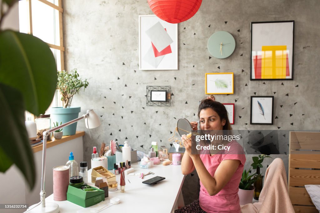 Woman tweezing eyebrows while having beauty treatment at home